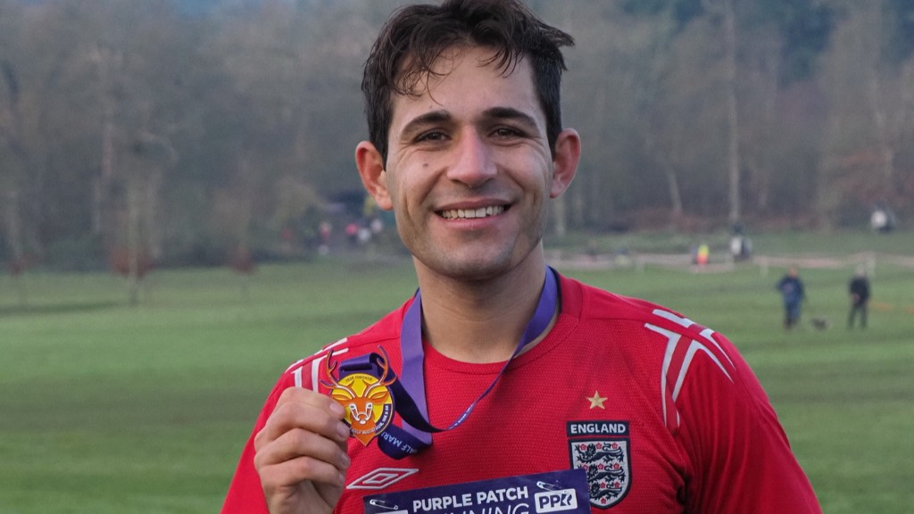 Hozan A young ,man in running gear holding a medal.