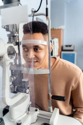 A patient having an eye test by machine (placing their chin on a rest).
